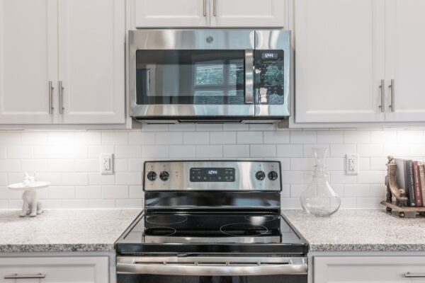 Kitchen In A Harpeth Square Apartment, It Shows White Cabinets, A Microwave An An Electric Stove.
