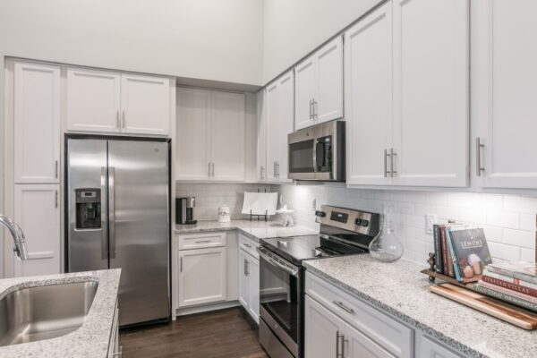 Kitchen In A Harpeth Square Apartment With All The Necessary Appliances, Such As A Sink, A Fridge, An Electric Stove And A Microwave.