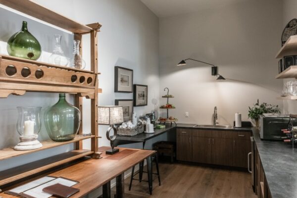 Different Angle Of The Kitchen In A Harpeth Square Apartment. It Has A Rustic, Comfy Feel. Shelves Are Made Out Of Wood. It Has Glasses, Plates, A Microwave. It Has A Sink.