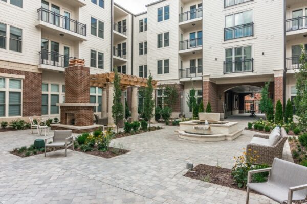 Different Angle Of The Outdoor Area Between Buildings In Harpeth Square. It Has Chairs And Tables, Plants And Trees.